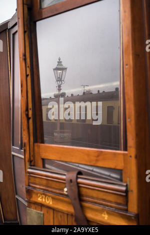 La riflessione della vecchia lampada a gas & treno vintage nella finestra di terza classe di teak vintage carrello ferroviario a fianco di vintage stazione ferroviaria piattaforma, UK. Foto Stock