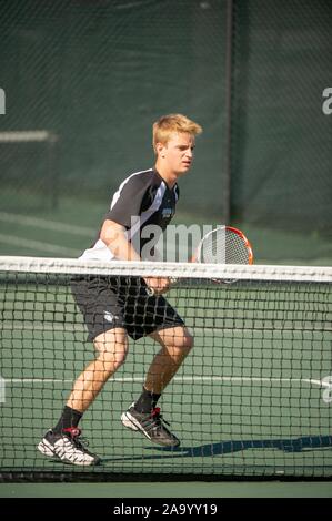 A tutta lunghezza shot di Johns Hopkins University uomini giocatore di tennis, su un tribunale aperto in una giornata di sole, di piegatura e la posizione di cambio come egli vigila la palla durante una partita con Kalamazoo College, 24 marzo 2010. Dall'Homewood raccolta di fotografie. () Foto Stock