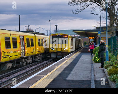 Un treno arriva come un altro treno attende sulla stazione di Hoylake sul Merseyrail elettrico ferroviario la rete di trasporto regionale rete dei " commuters " Foto Stock