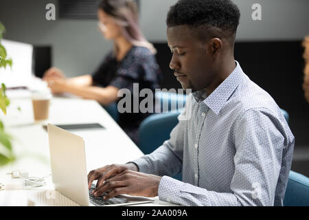 Concentrato americano africano maschile giovane sviluppatore che lavora in ufficio. Foto Stock