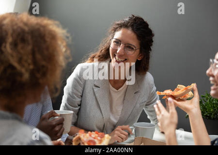Sorridente caucasian business donna godendo la pizza con i colleghi. Foto Stock
