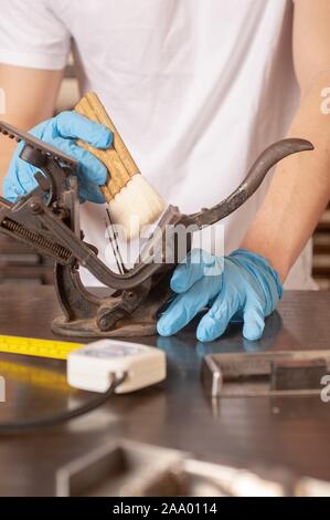 Un museo conservatore, indossando i guanti, utilizza una spazzola per pulire un artefatto di metallo, 2 febbraio 2009. Dall'Homewood raccolta di fotografie. () Foto Stock