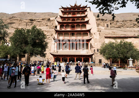 I turisti cinesi di fronte al Mogao grotte buddista Foto Stock