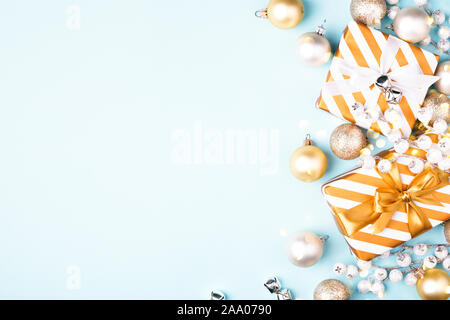 Composizione di natale con confezioni regalo e decorazioni dorate su sfondo blu. Appartamento laico, biglietto di auguri. Foto Stock