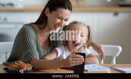 Sorridente giovane madre mostra fumetti divertenti per contentissimo figlia. Foto Stock