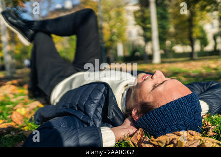 Felice giovane rilassante nel parco tra foglie di autunno. Foto Stock