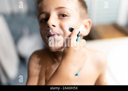 Little Boy la rasatura come un adulto in bagno di fronte allo specchio Foto Stock