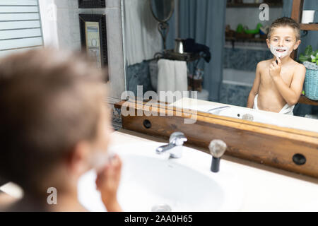 Little Boy la rasatura come un adulto in bagno di fronte allo specchio Foto Stock