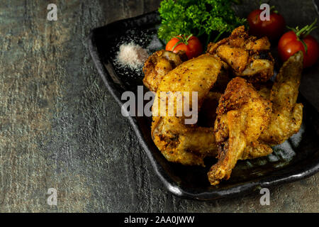 Fatti in casa, intervallo libero e organico olio di noce di cocco Alette di pollo fritte. Servita con pomodoro e belle sale himalayano guarnire con prezzemolo. Foto Stock