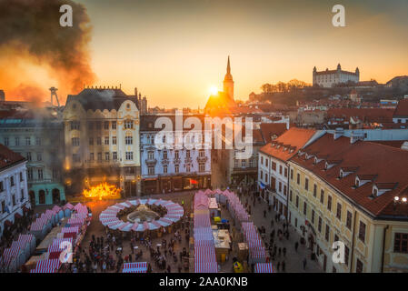 Fuoco e fumo in edificio storico sulla piazza principale, Bratislava, Slovacchia al tramonto con vari punti di riferimento in background Foto Stock