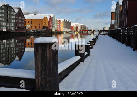 Trondheim in Norvegia Europa 18 Marzo 2017: Riverside proprietà si riflette in un fiume calmo e un waterside passerella coperta di neve. Foto Stock