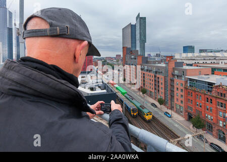 Appassionato di rampa / treno-spotter fotografare i treni a Manchester Oxford Road nel congestionato Castlefield viadotto nella zona centrale di Manchester Foto Stock