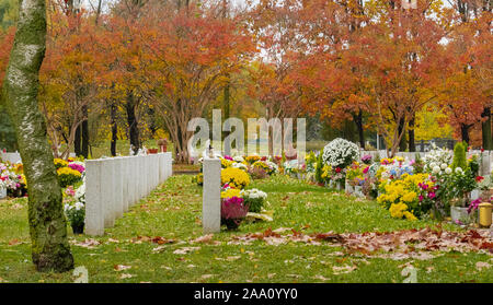 Cimitero giardino abbellito da vasi con fiori colorati sulle tombe in autunno Foto Stock