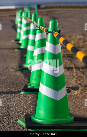 Green coni di sicurezza con strisce bianche poste in una riga, il fuoco selettivo Foto Stock