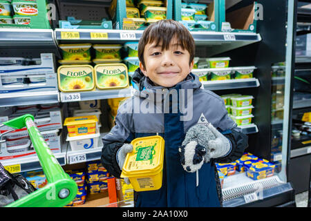 Un ragazzo in possesso di una vasca di diffusione di burro in un supermercato UK.giovani Foto Stock