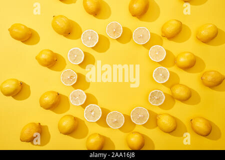 Vista superiore del taglio mature e limoni interi disposti in cornice rotonda su sfondo giallo con spazio di copia Foto Stock