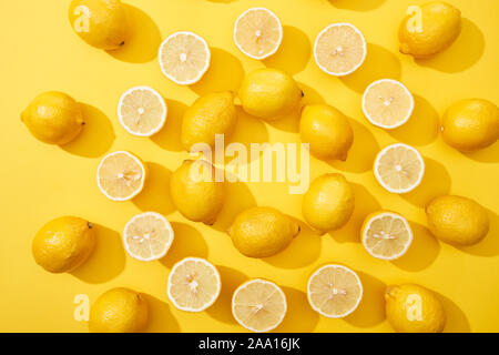 Vista superiore del taglio mature e limoni interi disposti in cornice rotonda su sfondo giallo Foto Stock