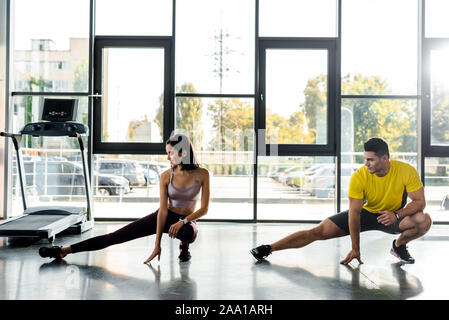 Sportivo e sportive facendo balzi in avanti insieme nel centro sportivo Foto Stock