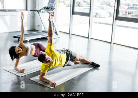 Sportivo e sportive facendo plank su tappetini fitness nel centro sportivo Foto Stock