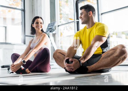 Sportivo sorridente e sportive stretching sui tappetini fitness nel centro sportivo Foto Stock