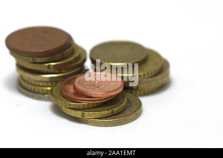 Parecchi Euro monete impilate in tre pali su una superficie bianca con spazio per aggiungere testi. Spazio di copia Foto Stock