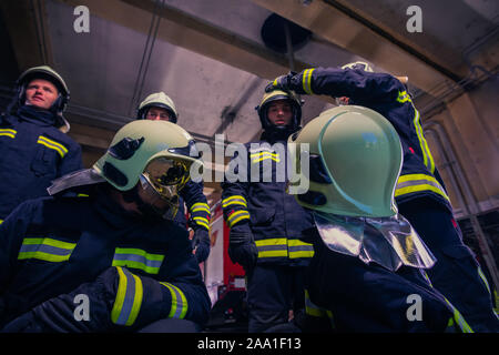 Ritratto di gruppo di vigili del fuoco che indossano uniformi di protezione all'interno della stazione dei vigili del fuoco Foto Stock