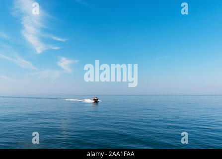 Crociera in barca sul mare lasciando sulla scia di una brillante giornata di sole. Bel cielo azzurro con luce nuvole bianche. Foto Stock