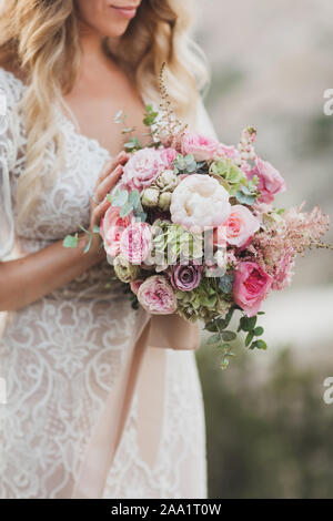 Sposa tenendo nelle mani di piccoli Bouquet nozze in colori pastello. La luce rosa rose e peonie bianco. Foto Stock