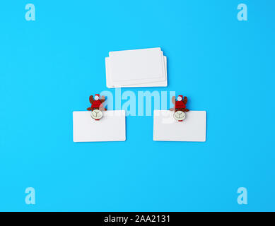 Svuotare il white paper le carte aziendali e vacanze clothespins su uno sfondo blu, vista dall'alto Foto Stock