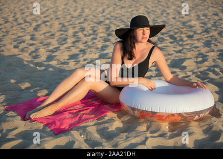 Donna anziana con una nuotata in un cerchio sulla spiaggia è in appoggio.Donna sunbathes nella sabbia.Vacanza al Resort Foto Stock