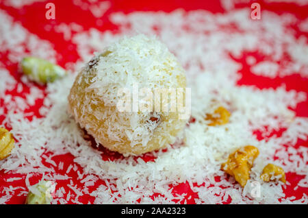 Polvere di noce di cocco cosparso di semolino Ladoo su una targhetta rossa con patatine fritte frutta secca Foto Stock