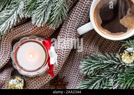 Piatto di Natale laici composizione con tazza di caffè, candela, decorazioni e abete su una felpa lavorata a maglia Foto Stock