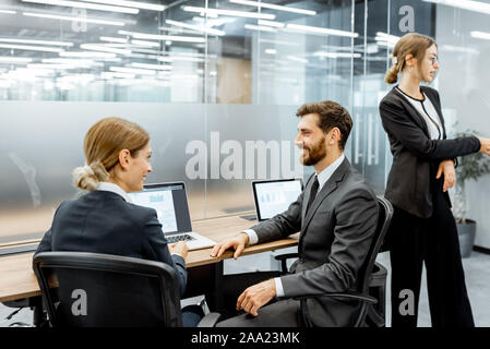 Bianco-collare i dipendenti al lavoro sul computer portatile presso il posto di lavoro nel reparto finanziario di una grande corporation, vista posteriore Foto Stock