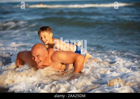 Papà e suo figlio andare in per lo sport in riva al mare. Un uomo sta spingendo fino in acqua. Vacanza attiva sulla spiaggia.Sport e Fitness Concept Foto Stock