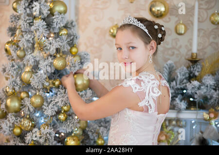 Smart girl decora un albero di Natale. Natale bambino con albero di Natale giocattoli Foto Stock