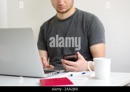 Giovane uomo seduto al tavolo utilizzando laptop Foto Stock