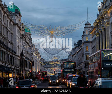 Christmas Angel decorazioni infilate su Regent Street, occupato con il traffico e i pedoni. Il centro di Londra, Regno Unito Foto Stock