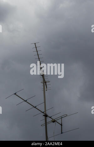 Un'antenna sulla parte superiore di un edificio sorge isolata contro un cielo di nuvole temporalesche immagine con spazio copia in formato verticale Foto Stock