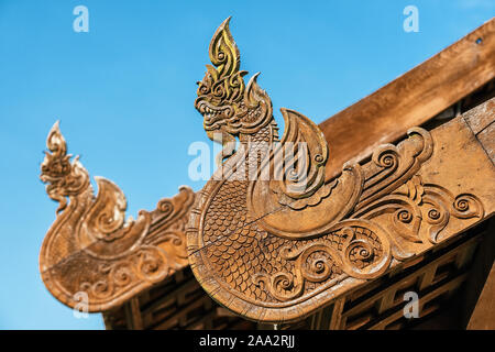 Draghi in legno decorazioni scolpite sul tetto del tempio buddista, Thailandia. Foto Stock