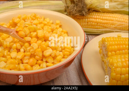 Chicchi di mais dolce in un piatto e spighe di grano sulla tavola di legno. Dieta sana. Dieta Fitness. Per una dolcezza. Close up Foto Stock