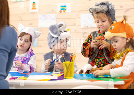 I bambini con insegnante fare mani artigianato in asilo nido. I bambini preparano per vacanze di natale e capodanno. Gruppo di i bambini in età prescolare sulla lezione in aula Foto Stock