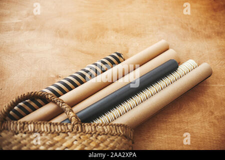 Elegante carta natalizia dei rotoli di paglia di stile rustico cesto su un tavolo di legno, copia dello spazio. Preparazione per le vacanze invernali. Craft, nero e oro wrap Foto Stock