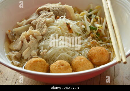 Vermicelli di riso topping sfera di gamberetti e slice bollito di maiale in zuppa mangiare da chopstick in legno Foto Stock