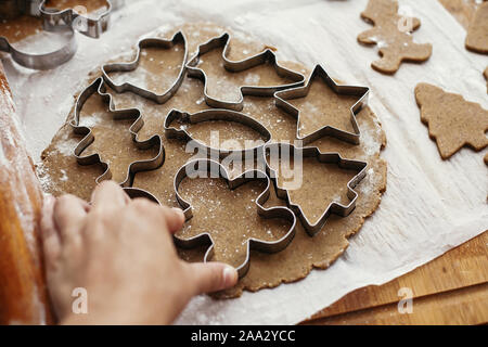 Far Natale gingerbread cookie. Taglio a mano impasto crudo con frese in metallo e anice, zenzero, cannella, pigne, rami d abete sul tavolo rustico Foto Stock