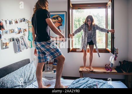Felice di amare giovane jumping letto avente il divertimento a casa - convivere, in amore, aventi il concetto di divertimento Foto Stock