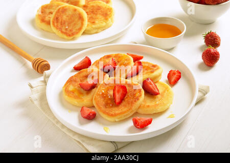 Cottage cheese pancake con fette di fragola e miele. Una sana prima colazione Foto Stock