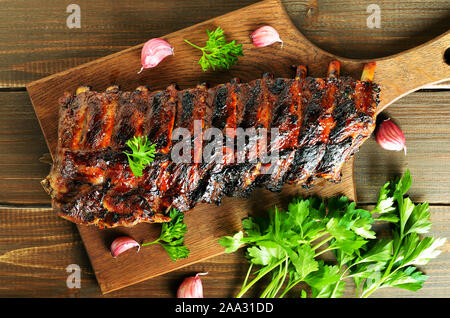 Grigliata di costolette di maiale sul tagliere. Vista superiore, piatto laici. Gustosi barbecue di carne. Foto Stock