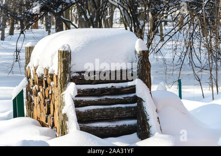Legna da ardere impilati in un bosco sotto la neve in una fredda giornata invernale, primo piano Foto Stock