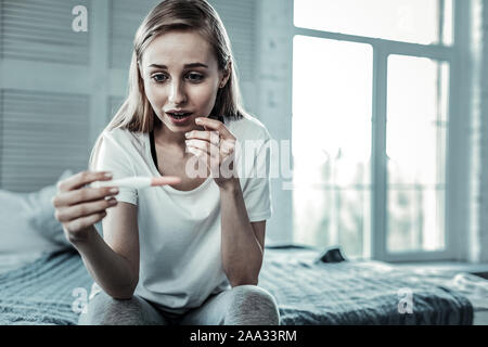 Bella Donna che guarda il test di gravidanza Foto Stock