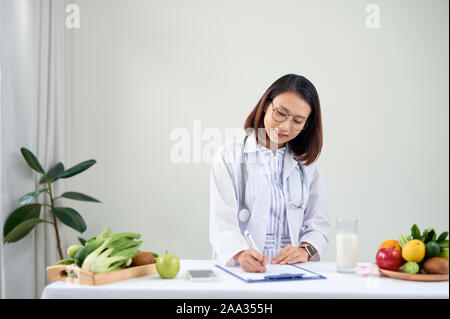 Nutrizionista femmina con frutti lavorando alla sua scrivania Foto Stock